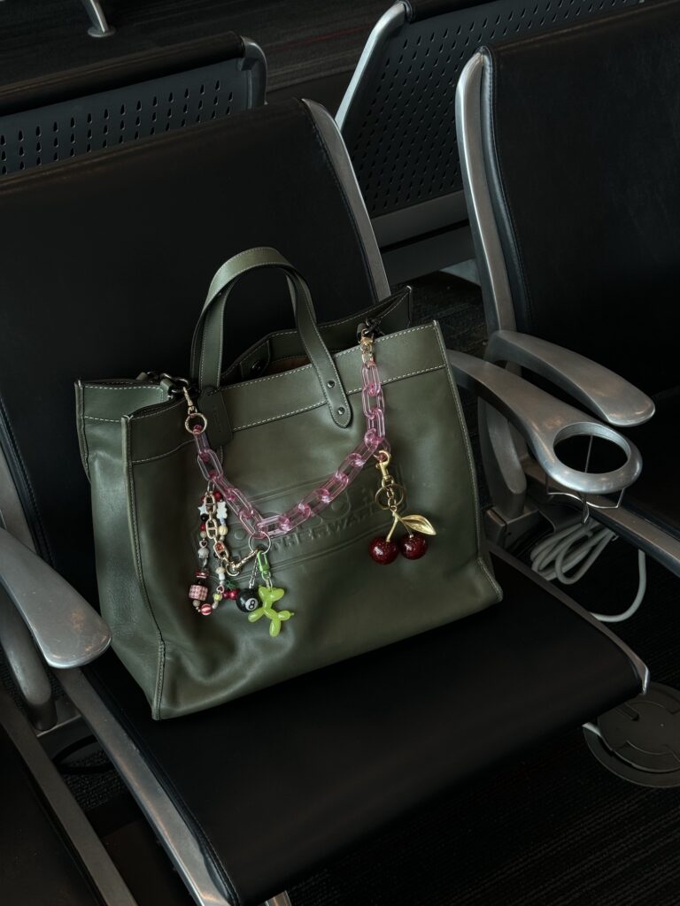 My green Coach tote, an anxiety bag styled with a pink chain-link keychain and cherry, beaded, and balloon dog charms.